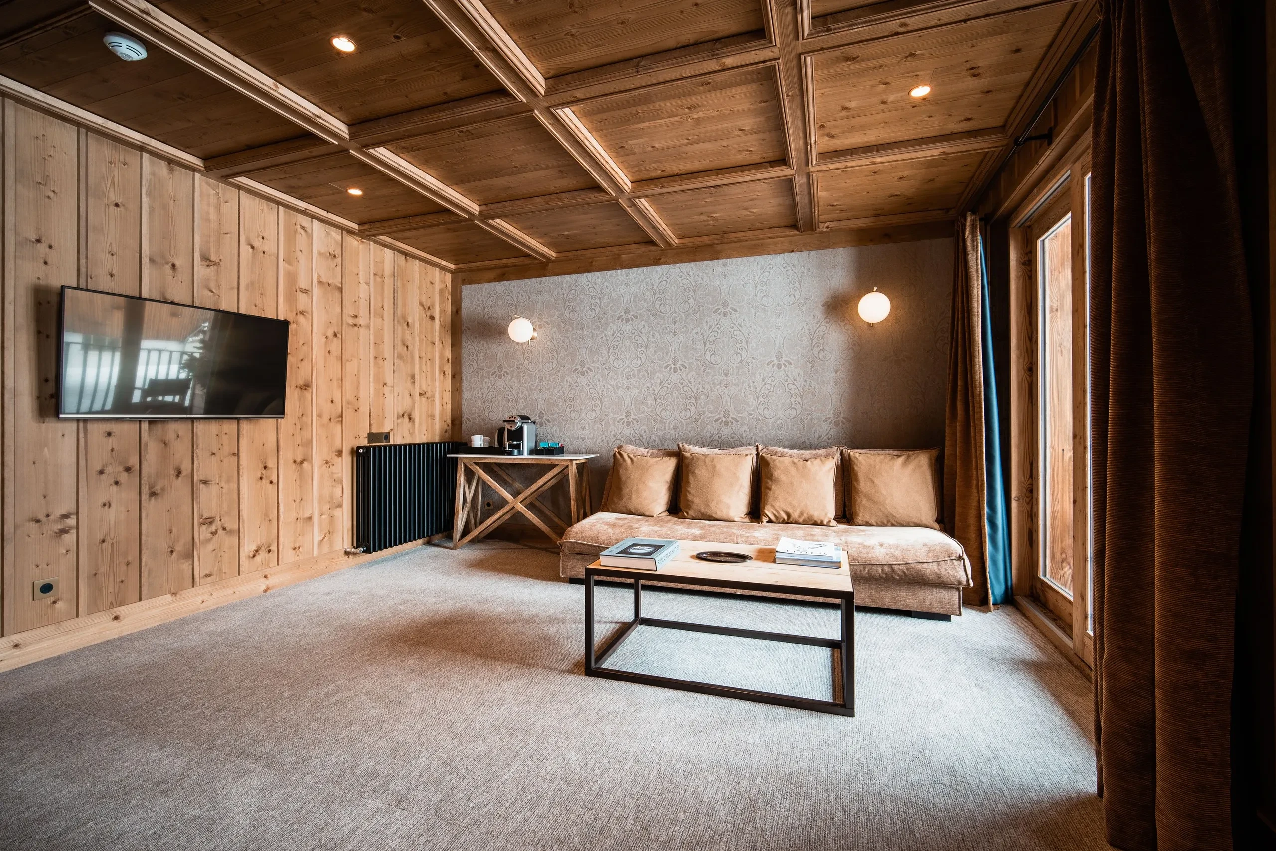 Salon en bois avec canapé et télé murale, Hôtel de luxe La Mourra à Val d’Isèr