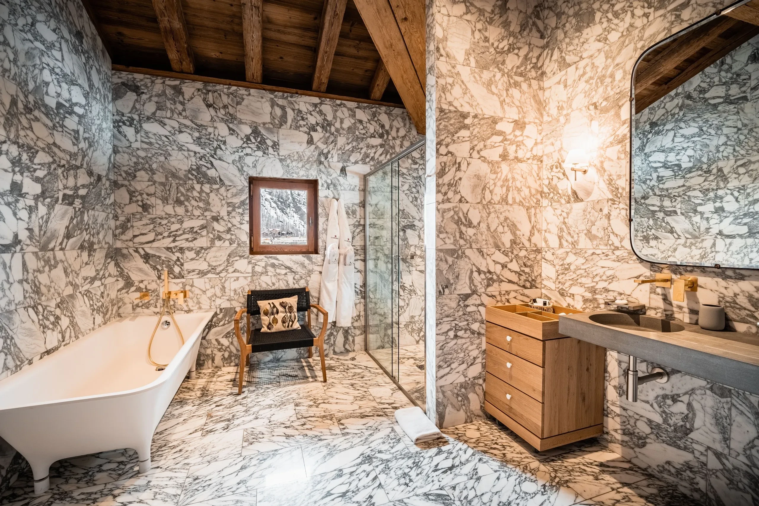 Salle de bain en marbre avec baignoire et douche, Hôtel de luxe La Mourra à Val d’Isèr