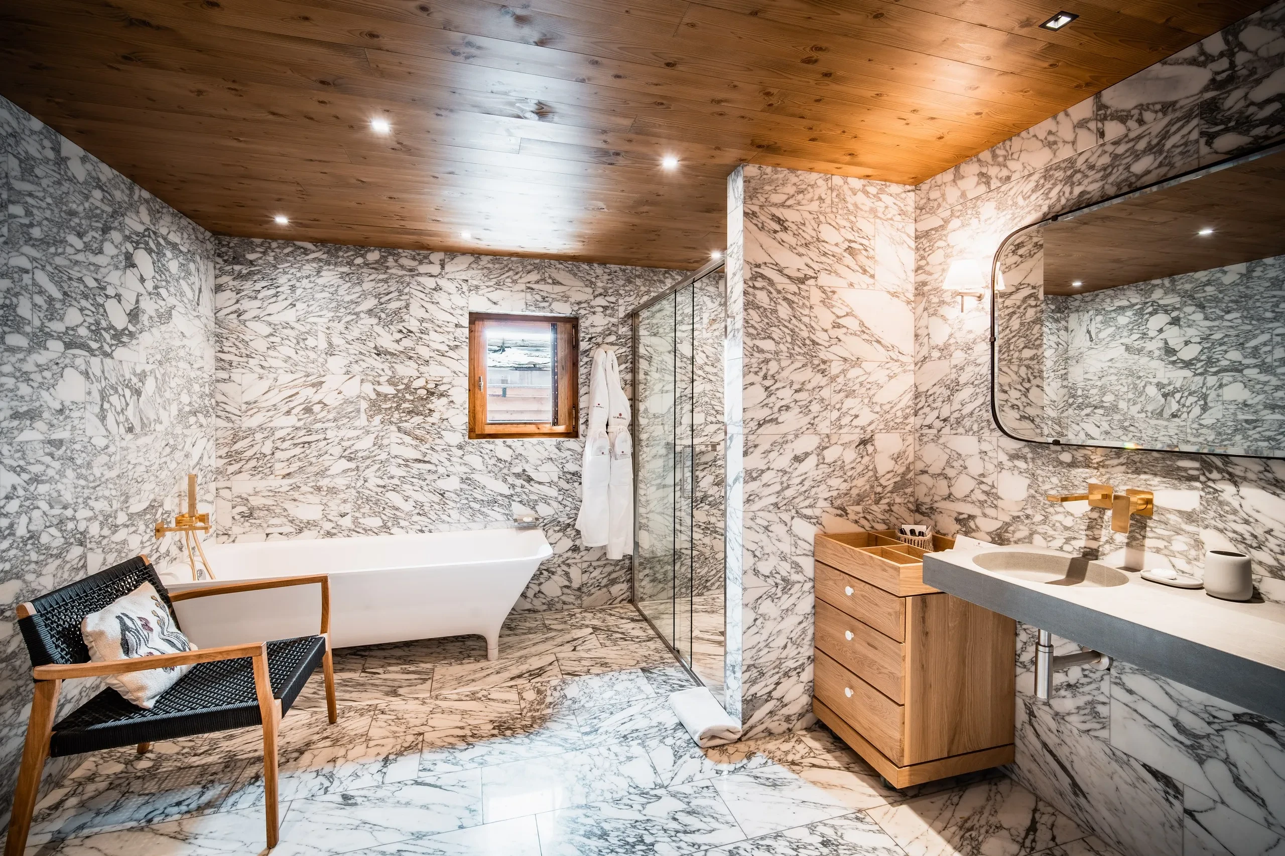 Salle de bain en marbre avec baignoire et lavabo, Hôtel de luxe La Mourra à Val d’Isèr