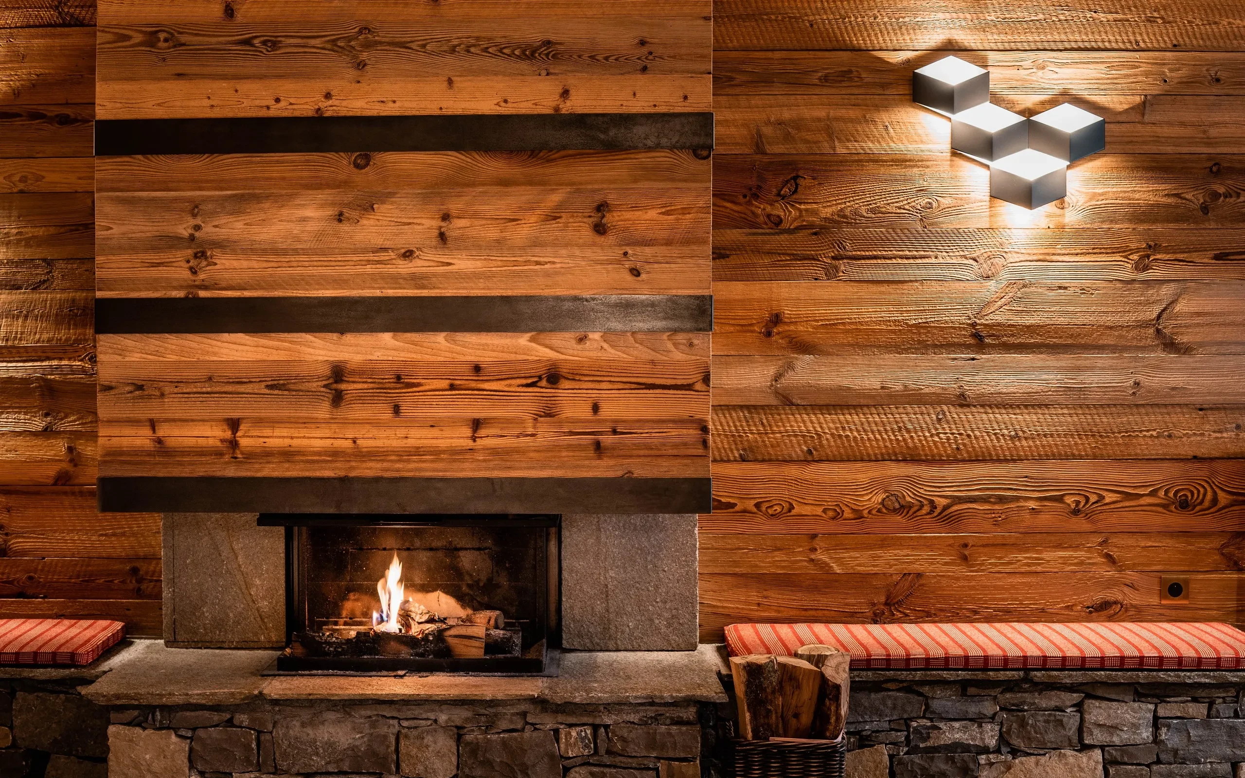 Cheminée moderne avec mur en bois et lumière, Hôtel de luxe La Mourra à Val d’Isère