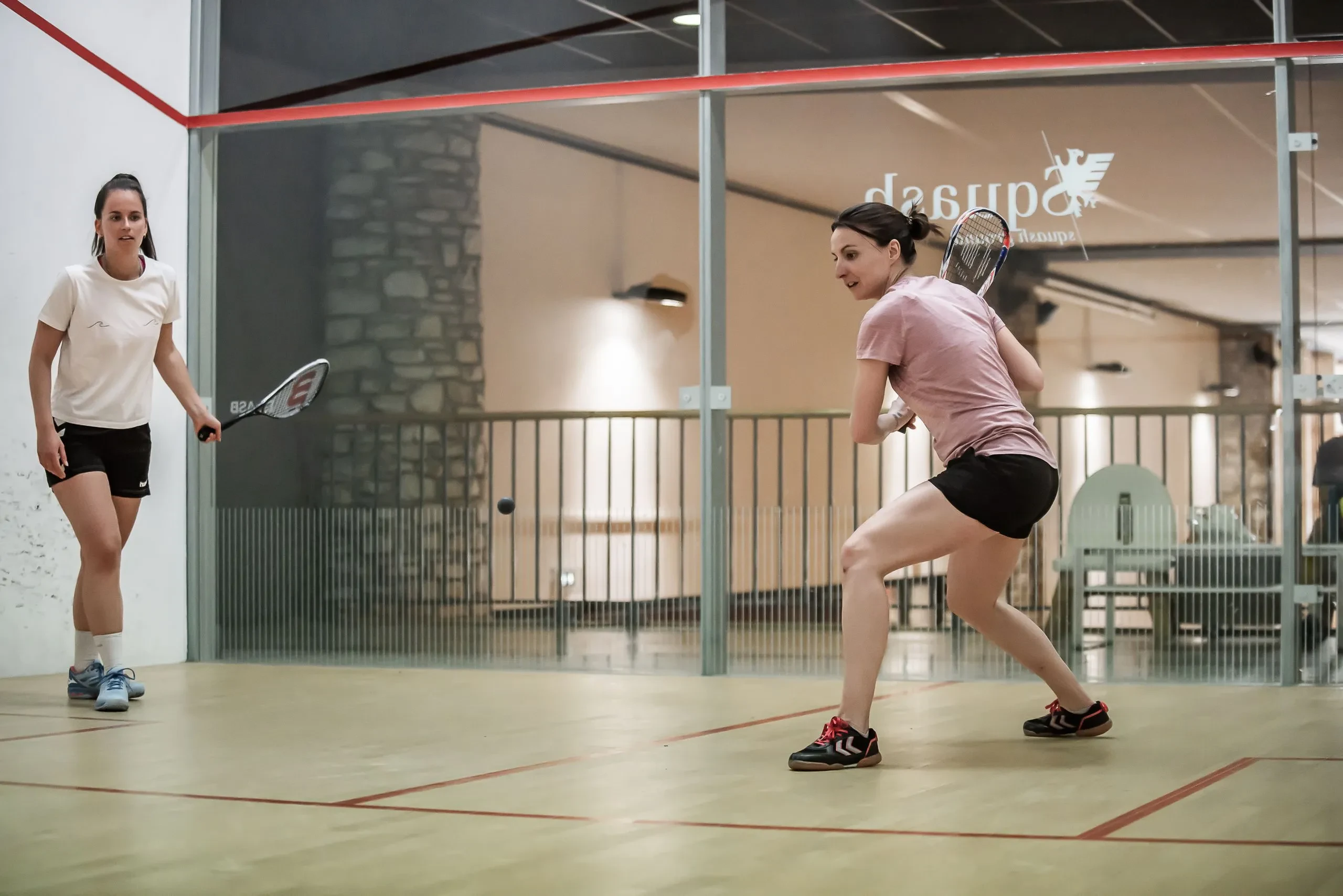 Deux femmes jouent au squash en intérieur, l'hôtel Village La Mourra pour un séjour à Val d’Isère