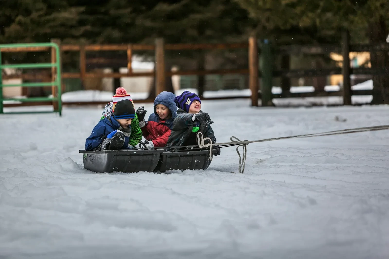 Enfants sur une luge tirée dans la neige, l'hôtel Village La Mourra pour un séjour à Val d’Isère