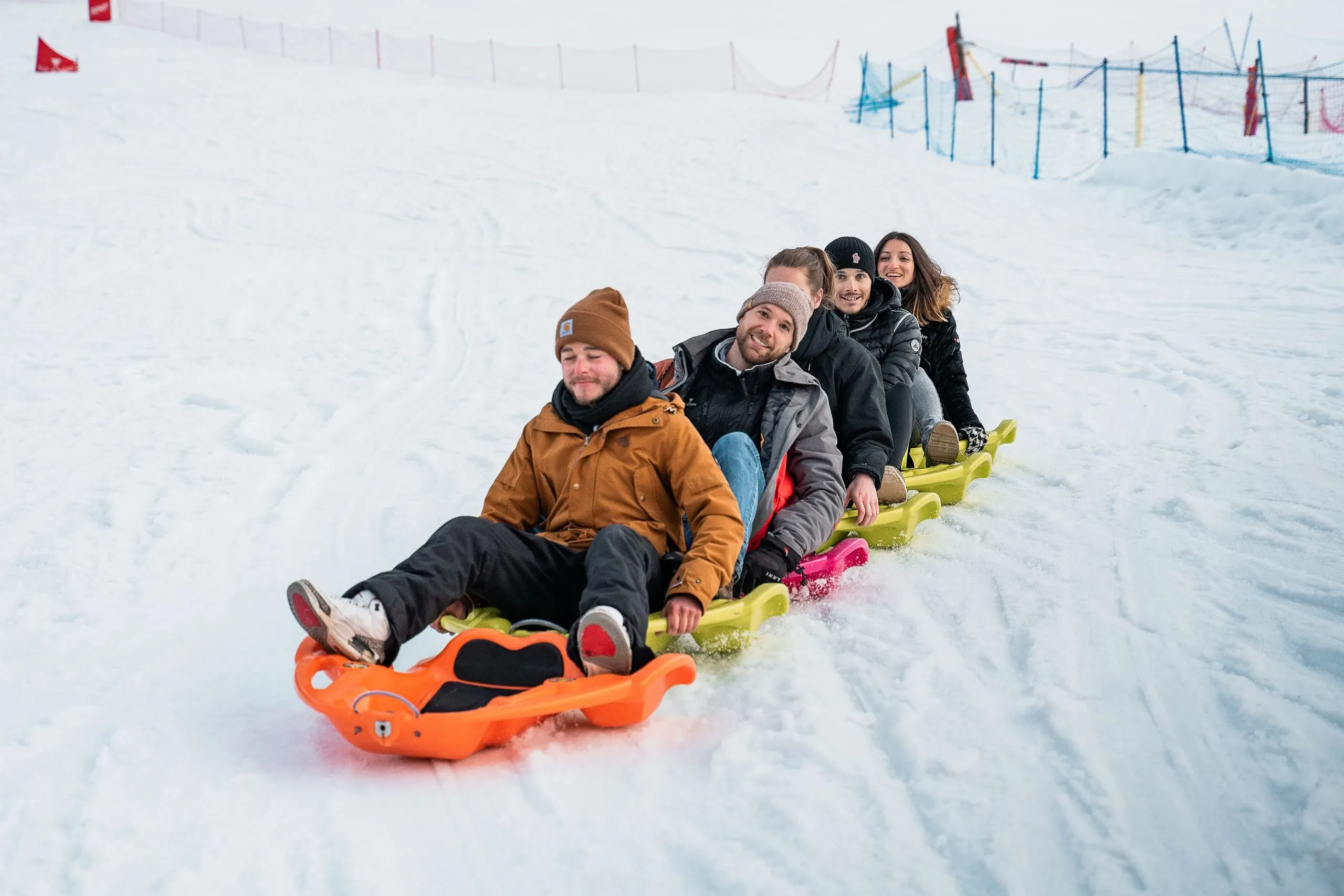 Cinq personnes font de la luge sur la neige, Hôtel à Val d’Isère avec piscine, La Mourra.