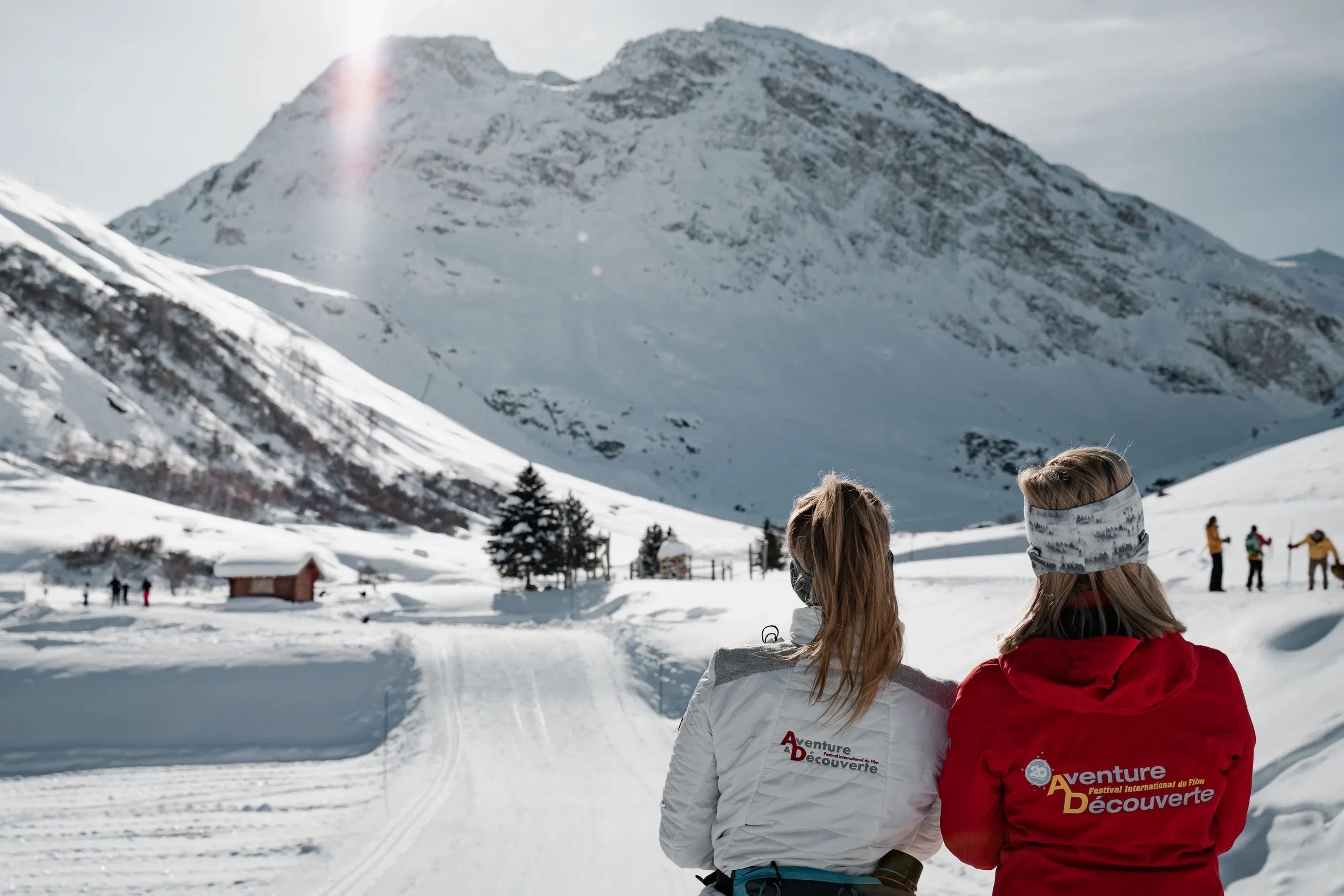 Deux femmes regardent paysage montagneux enneigé.