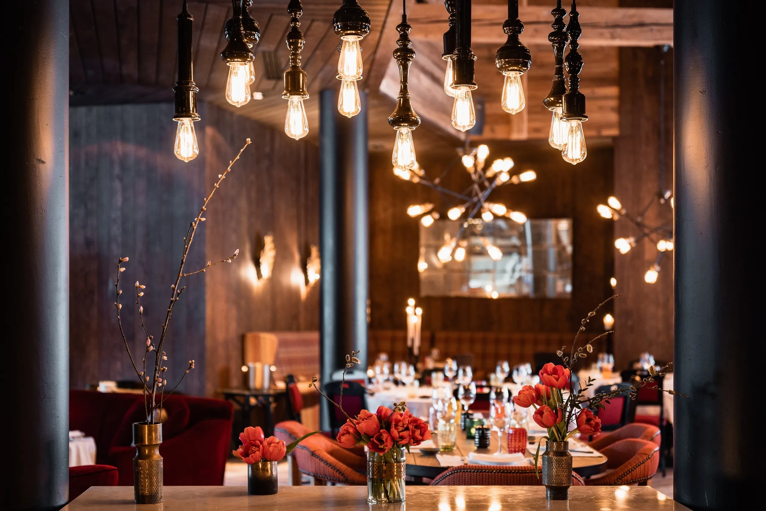 Restaurant élégant avec lumières et fleurs rouges.