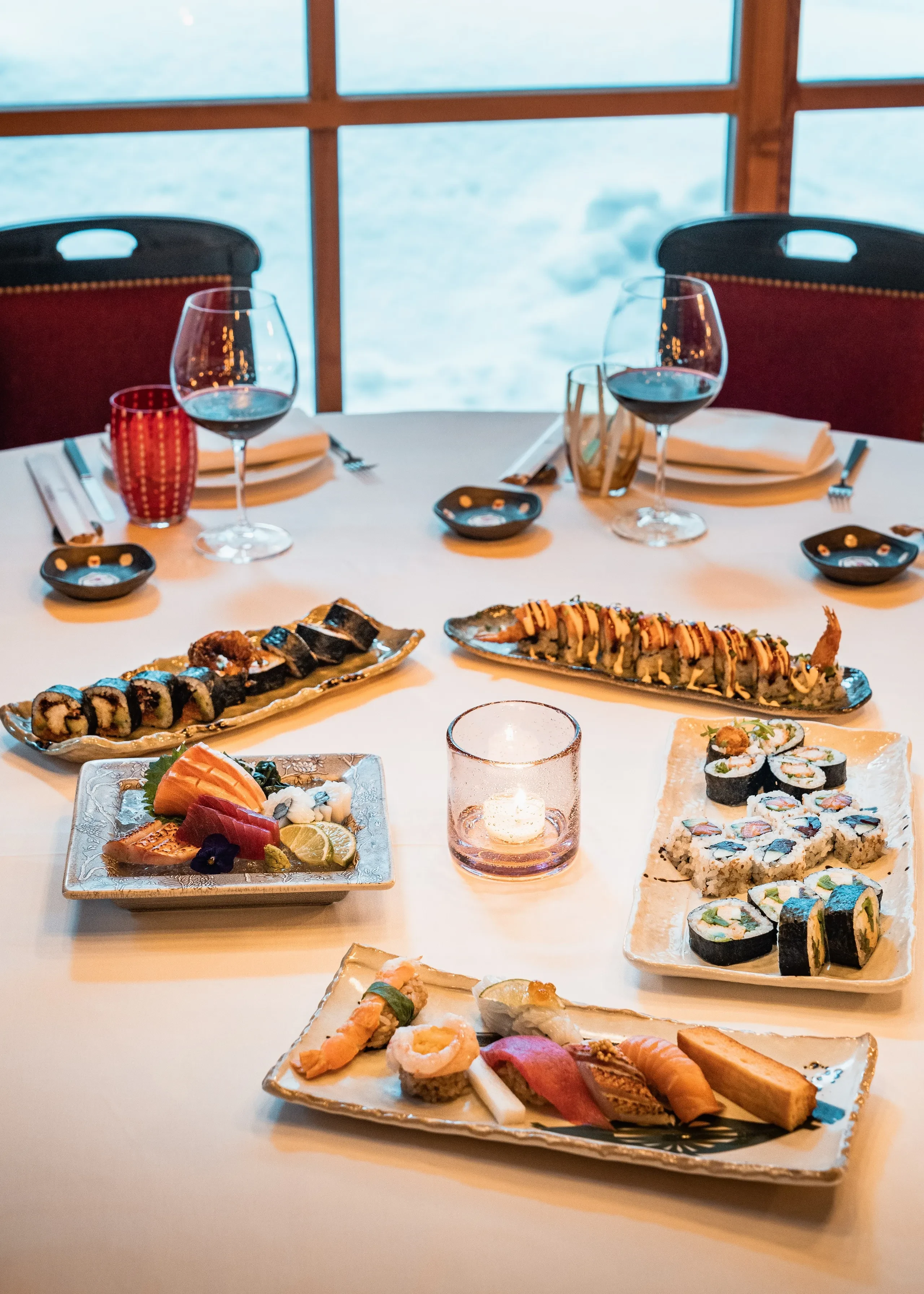 Table avec assortiment de sushis et vin rouge.