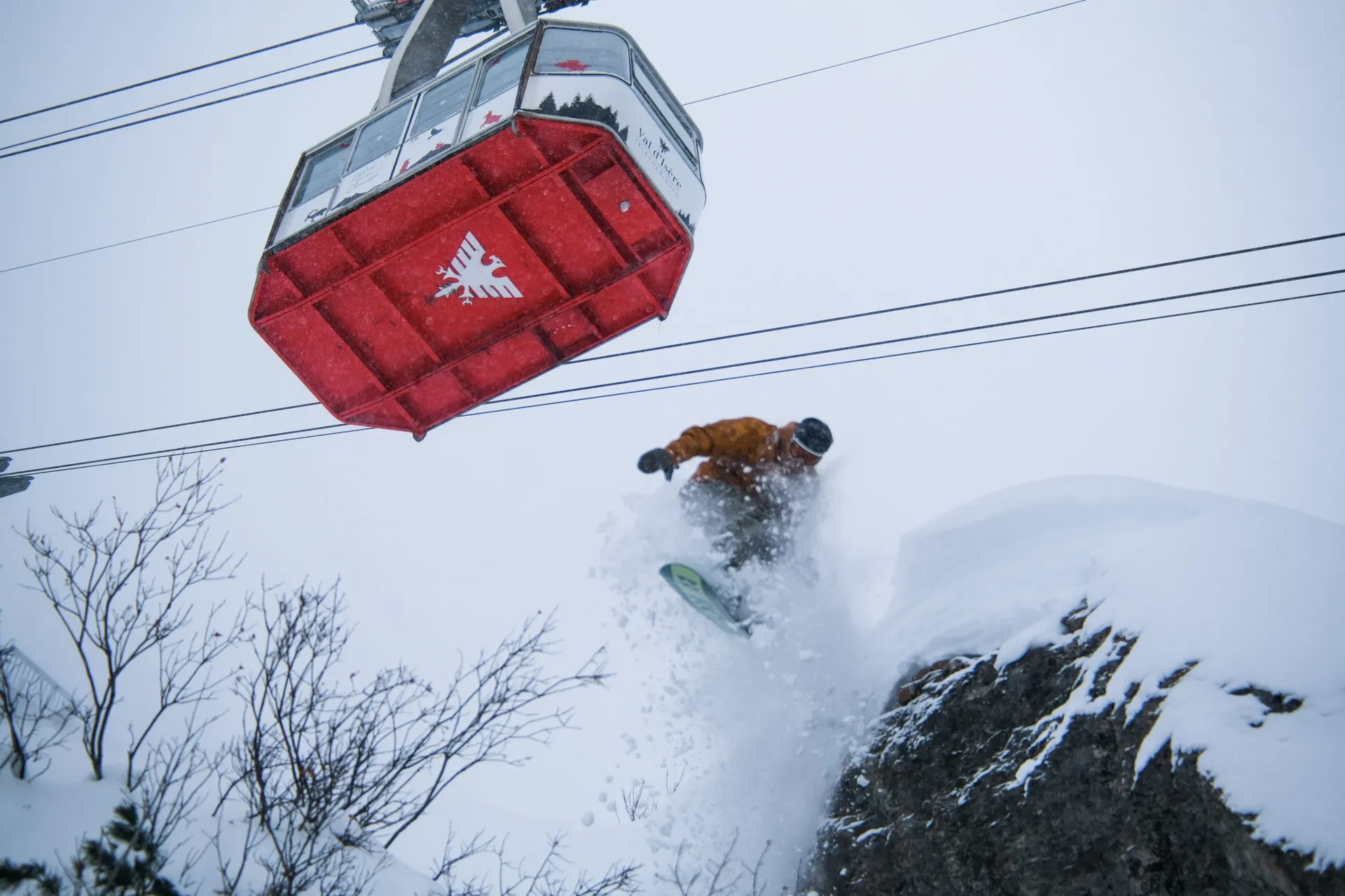 Snowboarder dévalant une pente sous un téléphérique rouge, Hôtel à Val d’Isère avec piscine, La Mourra.